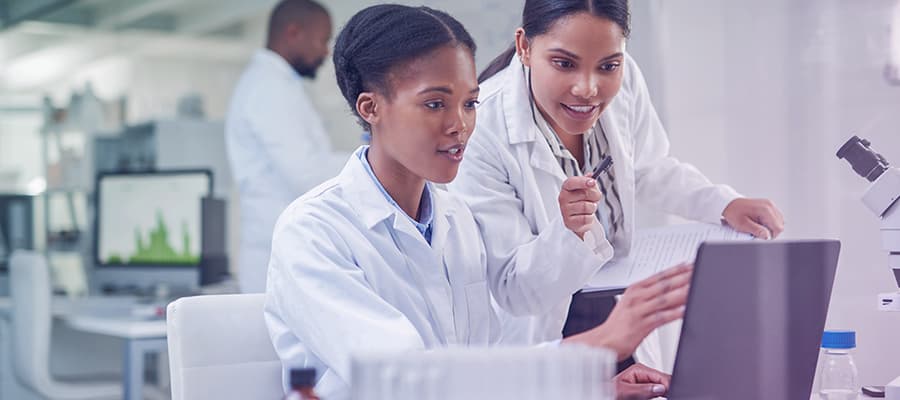 Image of two young pharma scientist using digital production records in a laboratory.