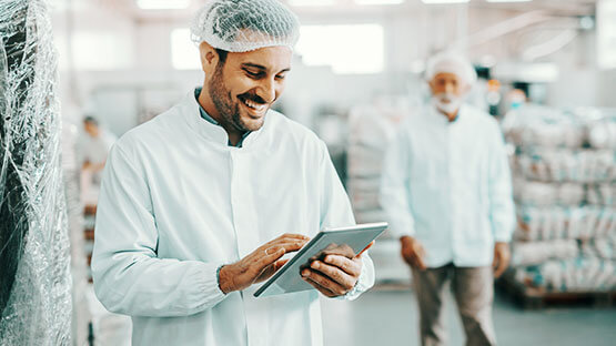 Manufacturing worker in lab coat using a tablet